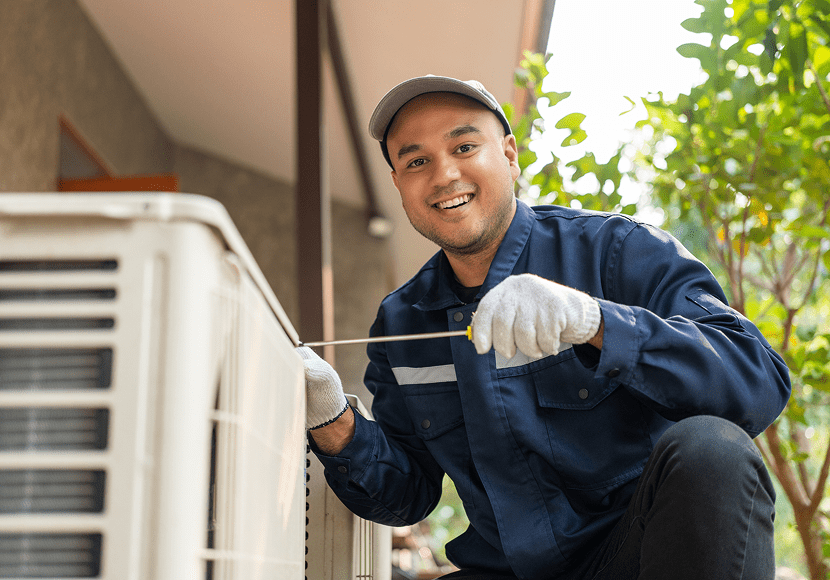 Smiling repairman fixing air conditioning system
